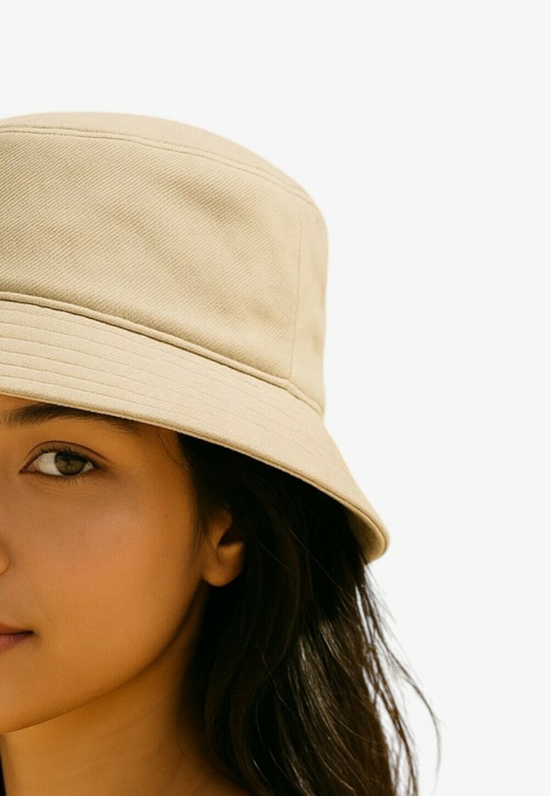 Cappello a secchiello beige in tessuto strutturato, con tesa larga e design strutturato. Finitura liscia, mostrato parzialmente indossato.