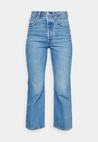 Jeans de tiro alto en azul claro con pierna recta y dobladillo sin acabar. Hechos de denim, con costuras de estilo vintage y cierre de botón.
