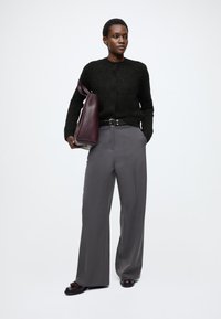 Czarny dziergany kardigan, szare dopasowane spodnie, ciemnobrązowe skórzane buty oraz bordo skórzana torba. Minimalistyczny design o luźnym kroju.