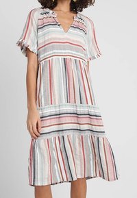 Gestreiftes Kleid aus leichtem Stoff; mit kurzen, gerafften Ärmeln, V-Ausschnitt und einem gestuften Saum in verschiedenen Farben, darunter Rot und Blau.