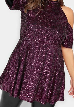 Robe en sequins violets avec manches courtes, corsage ajusté et jupe évasée. Le tissu a une texture brillante avec une couleur riche et profonde.