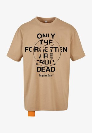 Beige Baumwoll-T-Shirt mit auffälligem schwarzem Text und grafischem Kreisdesign. Mit einem orangefarbenen Etikett am Saum. Boxy-Design, lockere Passform.