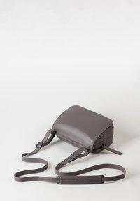 Borsa a tracolla in pelle grigia opaca. Forma rettangolare, sottile cinturino regolabile e chiusura con zip. Design minimalista con cuciture discrete.