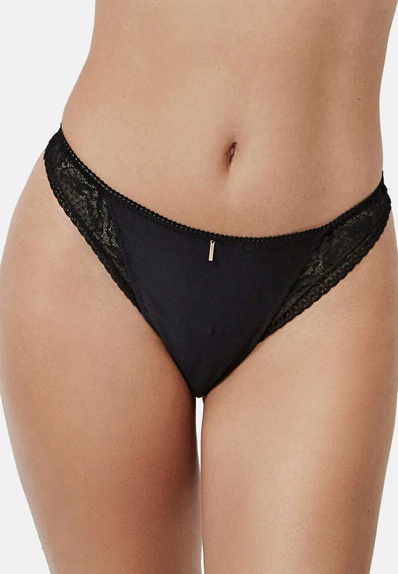 String noir à bordures en dentelle, présentant un corps en tissu lisse, des accents en dentelle délicate sur les côtés et un petit détail métallique à l'avant.