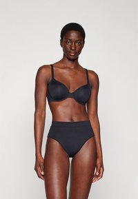 Conjunto de soutien preto e cuecas de cintura alta em tecido macio. O soutien tem aro e alças ajustáveis. Ambas as peças apresentam um design sem costuras.