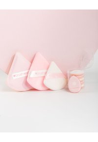 Tre spugnette triangolari per il trucco in rosa pallido e bianco, con un contenitore trasparente che contiene dischetti rotondi, con un logo sul lato.