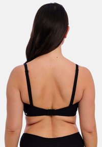 Černý bralet s tenkými ramínky, texturovanou tkaninou a zapínáním na háček a očko na zadní straně. Hladký povrch s minimem designových detailů.