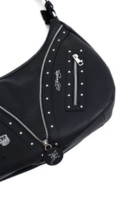 Zwarte hobotas van glad synthetisch materiaal, voorzien van zilveren studs, een ritsvak en een decoratieve logo-tag. Gebogen vorm.