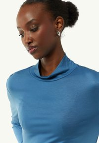 Turtleneck top in een levendige blauwe kleur, gemaakt van zachte stof met een aansluitende snit en subtiele glans. Beschikt over een omgeslagen kraagdetail.