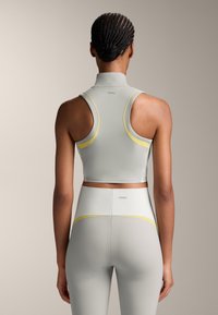 Sport bra and high-waisted leggings in light gray, featuring yellow accents and a fitted design. Smooth, stretchy material with a cropped style.
