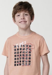Trumpu rankovu apelsinų spalvos medvilninė marškinėliai su juodu ir raudonu T-Rex grafiku ant tinklinio rašto, po kuriuo yra tekstas "T-REX KOROSHI".