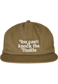Olive green cap with a flat brim, featuring white embroidered text that reads, “You can't knock the Hustle.” Cotton fabric with a textured finish.