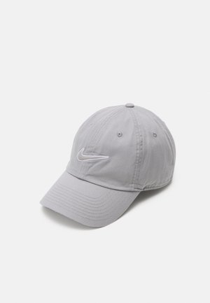 Casquette de baseball Nike gris clair avec visière incurvée et logo swoosh blanc brodé sur le panneau avant sur fond blanc uni.
