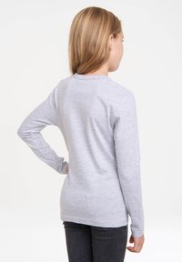 Long-sleeve gray shirt made of soft fabric, featuring a simple round neckline and a straight cut, worn with dark jeans.