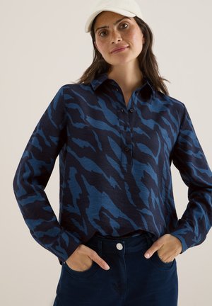 Camicia a maniche lunghe di colore blu navy con motivo a strisce di tigre blu, dotata di colletto con bottoni e patta centrale, abbinata a pantaloni blu scuro.