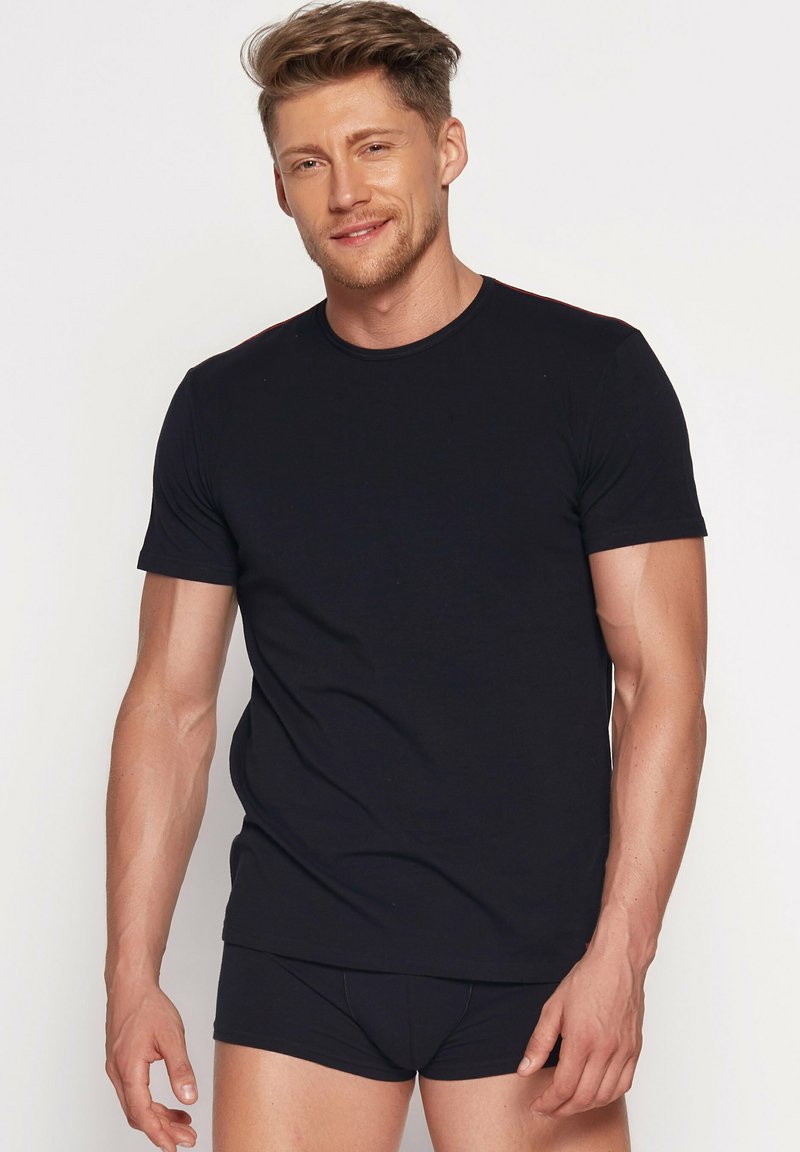 Black short-sleeve T-shirt made from cotton, featuring a round neckline and a smooth texture, worn with matching black underwear.