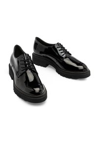 Zapatos oxford de charol negro con diseño de cordones, suela de goma elevada y detalle de costura en contraste a lo largo del borde.