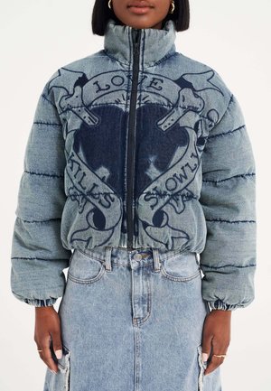 Denim pufferjack met hoge kraag, donkerblauw grafisch ontwerp met schedel en tekst, en elastische manchetten. Gecombineerd met een denimrok.