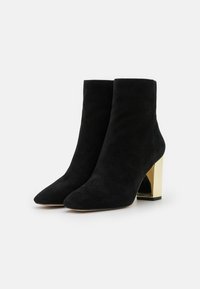 Bottes cheville en daim noir avec un bout pointu et un talon bloc rectangulaire doré brillant ; texture lisse sans motifs ni accents visibles.