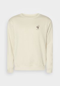 Crème-kleurige sweatshirt van katoenmix stof. Bevat een ronde hals en lange mouwen. Op de linkerkant van de borst staat een bedrukte leeuwenlogo met tekst.