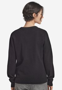 Czarny sweter dzianinowy z długimi rękawami, ściągaczami przy rękawach i u dołu oraz klasycznym okrągłym dekoltem. Gładka faktura z minimalnymi detalami.