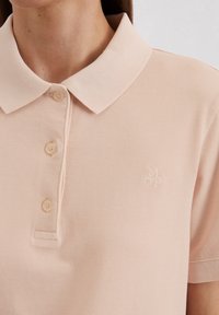 Polo shirt in lichtroze, gemaakt van textuurstof met een knoopsluiting en een puntige kraag. Voorzien van geborduurd "MOP" logo.