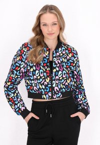 Giacca corta nera con motivo leopardato multicolore. Presenta una chiusura con cerniera frontale e polsini e vita a costine neri. Abbinata a pantaloni neri.