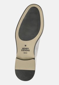 Semelle de chaussure en suede gris avec un fond noir en caoutchouc. Présente la marque "HENRY STEVENS" et "BERLIN" imprimées sur une semelle intérieure beige.