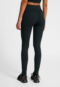 Zwarte leggings met een hoge taille, gemaakt van rekbare stof, met een gladde textuur. Het ontwerp bevat minimale stikdetails.