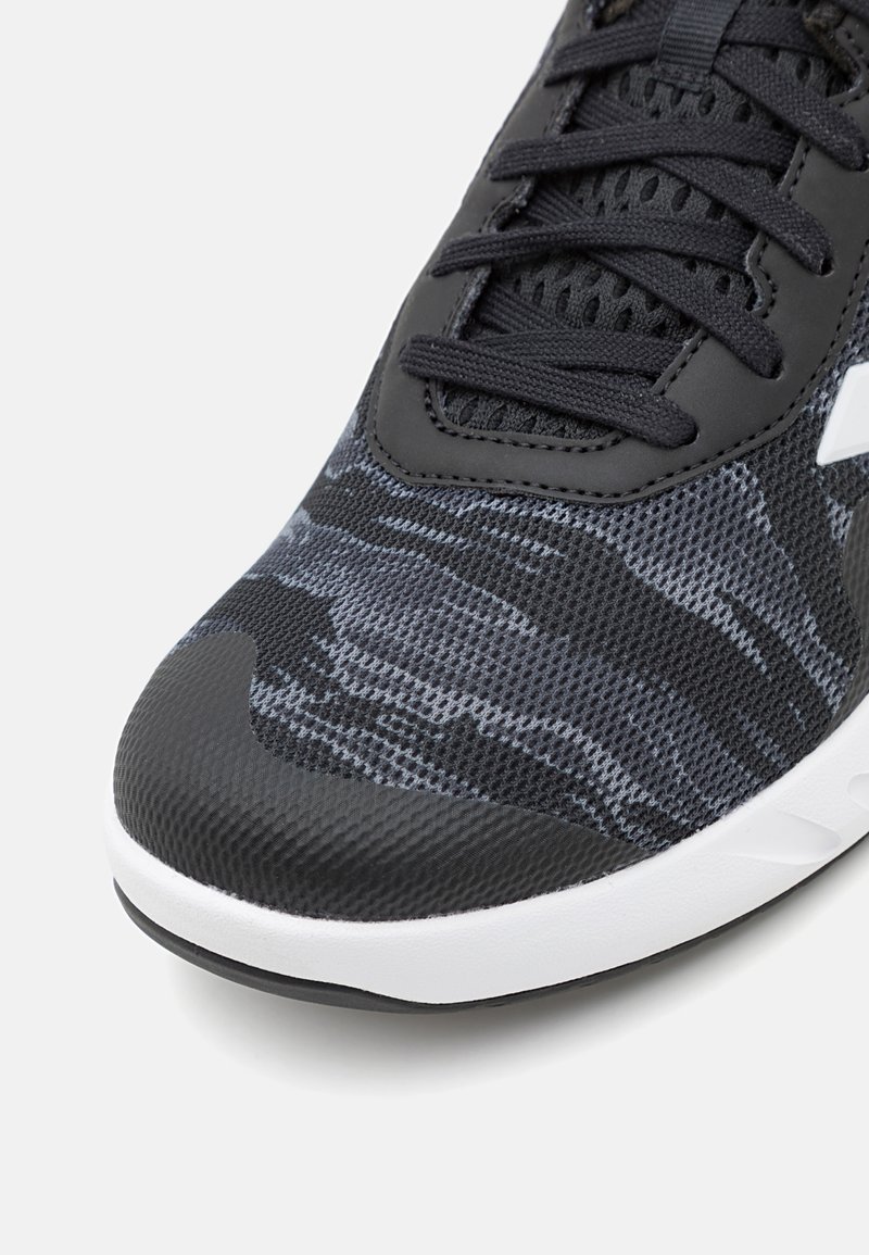 Schwarzer Sportschuh mit einem strukturierten Mesh-Obermaterial in Tarnmuster, flachen Schnürsenkeln und einer weißen Gummisohle für besseren Halt.