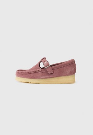 Suedesko i støvete rosa med sidebuckle, rund tå og en kontrasterende lys gummisåle. Minimalistisk design med tekstur.