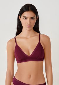 Brassière bordeaux en forme de triangle, avec des fines bretelles réglables et une bordure en dentelle le long du col et de la bande, fabriquée en tissu doux.
