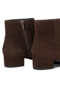 Brown suede ankle boots featuring a side zipper, a low block heel, and a smooth texture with a minimalist design.
