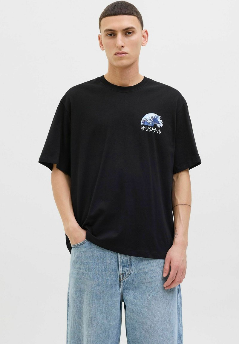 Camiseta de algodón negra con mangas cortas, que presenta un gráfico de ola y texto en japonés en el pecho izquierdo. Ajuste relajado, textura suave.
