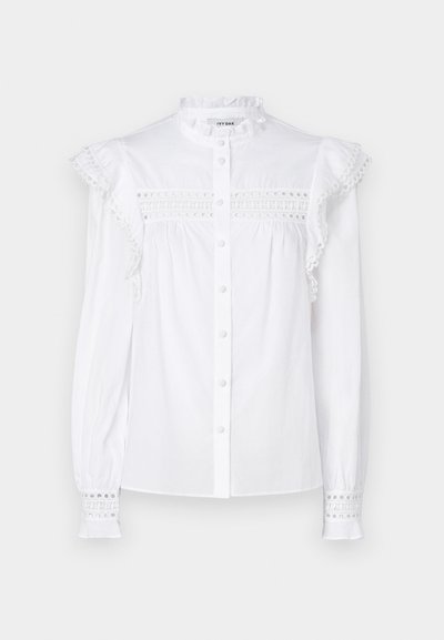 Vit långärmad skjorta med knäppt fram. Har volangkrage, broderat kantband och strukturerade detaljer vid ärmsluten. Gjord av lättviktsmaterial.