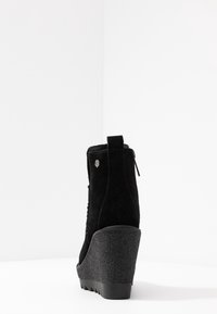 Klack-ankelboot i svart mocka, strukturerad klack, baktill zippered och öglflik. Plattformstil med rundad tå och solid sula.
