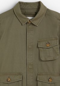 Chemise boutonnée vert olive avec col pointu et trois poches à rabat sur le devant, fermées par des boutons marron.
