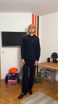 Ensemble en velours côtelé bleu marine avec une chemise à boutons et un pantalon assorti. La chemise présente des motifs subtils. Des chaussures marron viennent compléter le look.