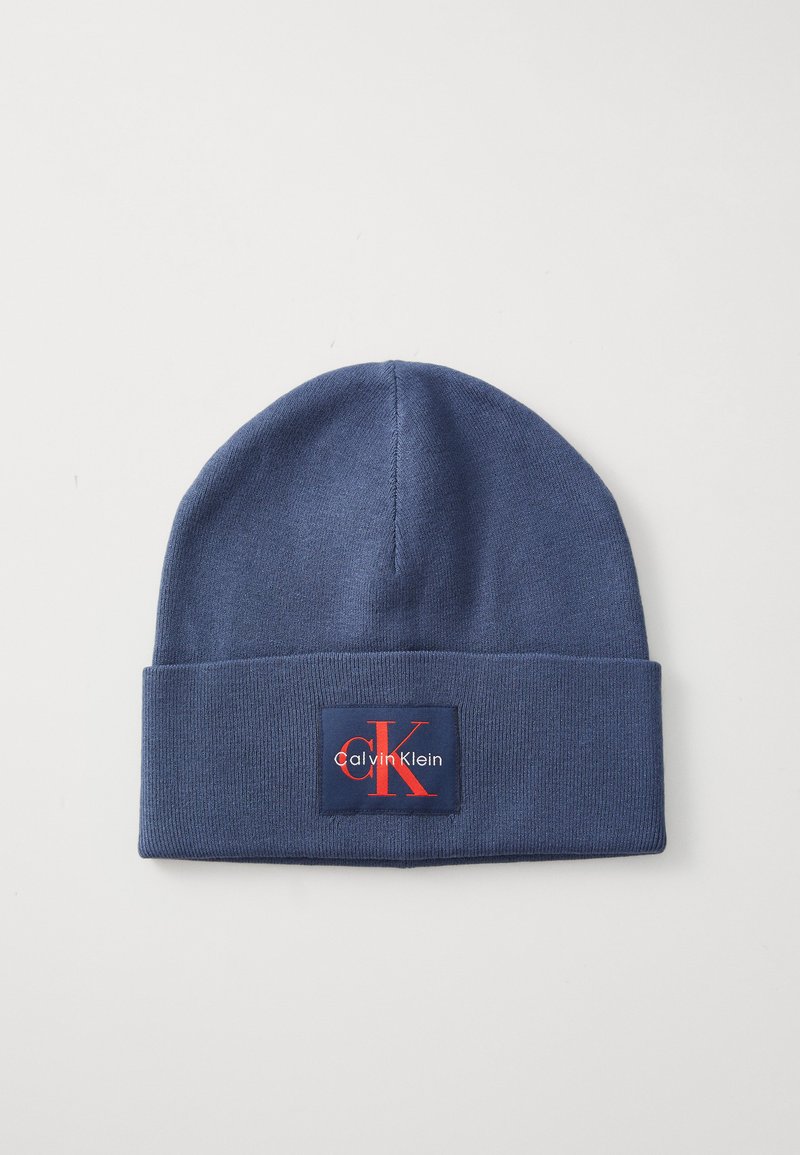 Berretto lavorato a maglia blu navy con risvolto, caratterizzato da una toppa rettangolare in rosso e bianco con la scritta "Calvin Klein" e "CK."