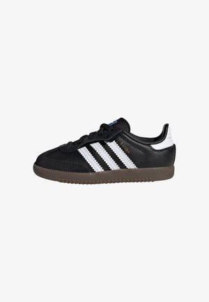 Czarny sneaker Adidas Samba z białymi paskami, brązową podeszwą i białą zakładką na pięcie, pokazany z profilu z prawej strony.
