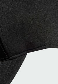 Černá elastická tkanina s hladkou texturou, zvýrazňující zakřivené kontury a zpevněné švy. Bezešvý design, minimálně viditelné zapínání.