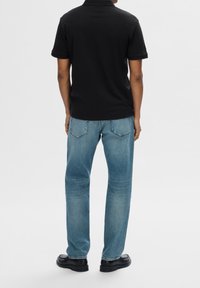 Svart pikétröja, kortärmad, kombinerad med ljusblå jeans. Slim fit, avslappnad design och slät textur. Svarta skor fulländar outfiten.