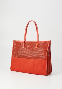 Sac fourre-tout en maille rouge avec des poignées en cuir lisse, de forme rectangulaire, à ouverture supérieure et présentant une texture à motifs. Comprend une section inférieure unie.