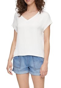 Top bianco a maniche corte con scollatura a V, dal taglio rilassato, realizzato in tessuto leggero, abbinato a pantaloni corti in denim blu chiaro con risvolto.