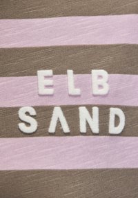 Gestreifter Stoff mit breiten braunen und hellrosa Streifen. Die weißen, strukturierten Buchstaben bilden im Zentrum die Worte "ELB SAND".