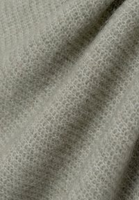 Hellgrauer Strickstoff mit einer weichen, flauschigen Textur und einem leicht offenen Gewebe. Das Material wirkt warm und gemütlich mit subtilen Variationen.