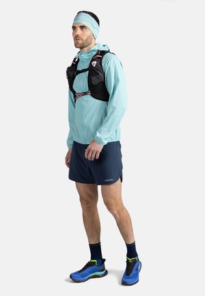 Lichtblauwe windbreaker, zwarte hydratatievest, marineblauwe shorts, blauwe hardloopschoenen met groene accenten. Glad textuur, verstelbare banden, atletische pasvorm.