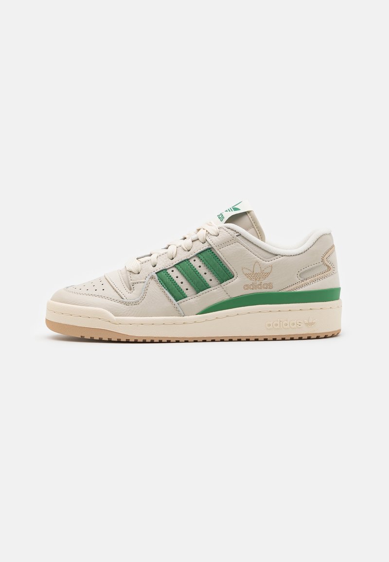 Cream-colored sneaker with green accents, featuring leather upper, perforated toe box, three striped detailing, and a rubber sole.