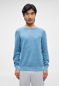 Ανοιχτό μπλε πουλόβερ με υφή στο πλέγμα, στρογγυλή λαιμόκοψη και ριπές στους καρπούς και στο στρίφωμα. Μικρή λεπτομέρεια λογότυπου στο στήθος.