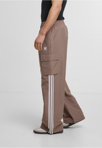 Bruna cargo-byxor med vita randdetaljer, elastisk midja och sidofickor; designade med en avslappnad passform och slät textur.